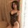 Woman in black lace teddy lingerie, sheer open-crotch design, posing by window with soft light.