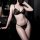 Woman wearing sexy black lace bikini set with sheer mesh and elegant trim in a dark bathroom setting.