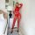 Woman modeling red lace bodysuit with sheer mesh panels in a bedroom setting.