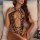 Woman lounging on beige couch wearing sexy leopard print bodysuit with sheer tight all-in-one lingerie design, highlighting p...