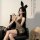 Woman wearing sexy leopard print lingerie set with bunny ears, posing seductively on black leather chair for role play or dat...