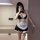 Woman wearing black and white maid-style lingerie set with lace trim, apron, choker, and garter for bedroom roleplay.