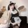 Woman wearing black and white sexy maid costume lingerie set with lace trim, cat ears headband, holding tray, posing on sofa.