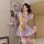 Woman wearing a sexy maid costume with ruffled apron and sweet chef-inspired lingerie set, posing in a cozy room.