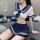 Woman wearing a navy and white sailor-style crop top and pleated skirt, styled as a sexy maid costume for role play.