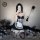 A woman poses in a black and white maid costume set, featuring lace details and stockings, holding a feathered accessory amid...