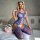 Woman wearing blue mesh bodysuit and fishnet stockings, posing on bed with flowers—sexy, elegant lingerie set.