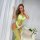 Woman wearing neon green mesh lingerie set with sheer lace bodysuit and fishnet stockings, posing elegantly by white curtains...