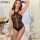 Woman wearing a black sheer lace bodysuit with a high-waist design, posing elegantly in a romantic setting.