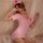 Woman wearing pink nurse costume lingerie with red cross cap, posing seductively on bed with lace details and open-crotch des...