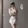 Woman in white sexy nurse costume lingerie set with bow-tie skirt and round neck top, posing seductively.
