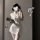 Woman in white nurse costume lingerie set with bow-tie skirt, round neck top, and matching hat, holding a clutch.