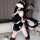 Woman wearing black lace nurse-maid costume with apron, holding whip, for adult role play.