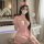 Woman in pink nurse costume with lace-up front, seated in bathroom; includes hat and mask for couples bedroom play.