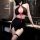 Woman wearing a black and red sexy nurse costume with halter neck, cross details, and fishnet stockings in a modern bathroom ...