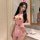 Woman modeling pink sexy nurse costume with red cross details, featuring a seductive seamless bodysuit and busty illusion des...