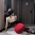 Woman in black and red bodycon skirt with black stockings, posing on a white rug in a modern room.