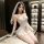 Woman in white lace bridal bodysuit with veil, thigh-high stockings, and open-crotch design for intimate wear.