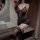 Woman wearing black lace sleepwear set with deep v-neck bodysuit and elastic strap nightgown, holding a red rose.