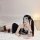 Woman lounging on bed in black and white maid costume set with lace trim, headpiece, and garter straps.