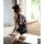 A woman sits by a window wearing a black floral printed cheongsam lingerie, holding a feather. the design features a halter n...