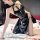 Woman in black pvc catwoman costume with lace-up bodysuit, garter belt & thong lingerie for role play on bed.