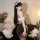 Woman in sexy maid lingerie set with sheer backless design, white ruffled top, black lace skirt, and floral headband.
