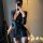 Woman in black pinstripe sexy secretary costume outfit with deep v-neck and thigh-high slit, posing for mirror selfie.
