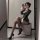 Woman in striped secretary costume with black heels, posing on a checkered stool.