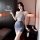 Woman in gray sheer lingerie skirt and matching sleepwear set, holding wine bottle, elegant bedroom setting.
