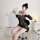 Woman wearing sheer black bodycon corset dress with straps, posing in boudoir setting.