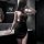Woman in black sheer halter bodycon dress posing in bathroom.