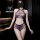 Woman modeling purple sheer lace bodysuit set with mesh tear-away thong design in modern bathroom setting.