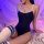 Woman wearing black sheer milk silk bodysuit with white trim, paired with striped thigh-high socks, posing on fluffy rug unde...