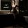 Woman wearing a sexy sheer open-crotch bodysuit in a dimly lit bathroom, showcasing the transparent lingerie outfit’s seducti...