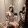 Woman wearing sexy sheer sleepwear bodysuit with lace details and bunny ears, posing seductively in a modern room.