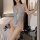 Woman in blue lace sheer bodysuit with cutouts, holding flowers in bedroom.