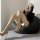 Woman lounging on black bean bag chair wearing shiny black fishnet stockings with tear-away crotch, paired with high heels an...