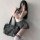 A stylish individual poses with a black leather bag, wearing a white top with a bow tie and a gray pleated skirt, embodying a...