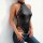 Woman wearing glossy black pvc halter bodysuit with side lace-up ties and backless design, paired with jeans.