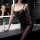 Woman wearing a sexy transparent black bodysuit and stockings set in a modern bathroom setting.