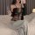Woman wearing a sexy transparent lace bodysuit with an open-crotch design, paired with a black cardigan and gray pants, sitti...
