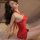 Woman wearing red lace cheongsam lingerie set with hook-neck design, posing seductively on bed — vintage bodycon sleep dress.