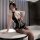 Woman wearing black pvc lace bodysuit with gold trim, sheer gloves, and airline stewardess hat for role play or intimate wear...