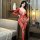 Woman wearing red sheer lace open-crotch bodysuit with floral embroidery and tear-away design in bedroom setting.