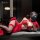 Woman in red lace sleepwear set with gloves and stockings, lying on bed. premium silk-look lace flagpole sleepwear set - sedu...