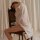 A woman sits on an antique chair draped in a sheer white silk shirt, evoking sensuality and elegance. the soft fabric and rel...