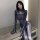 Woman in sleek black spider-man cosplay bodysuit with web pattern, posing seductively indoors.