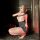 A woman poses in a mirror wearing a black bodycon dress with sheer lace details, paired with stockings and high heels, embody...