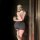 A woman poses in a mirror wearing a black bodycon dress paired with sheer stockings and ballet flats, holding a phone. the ou...